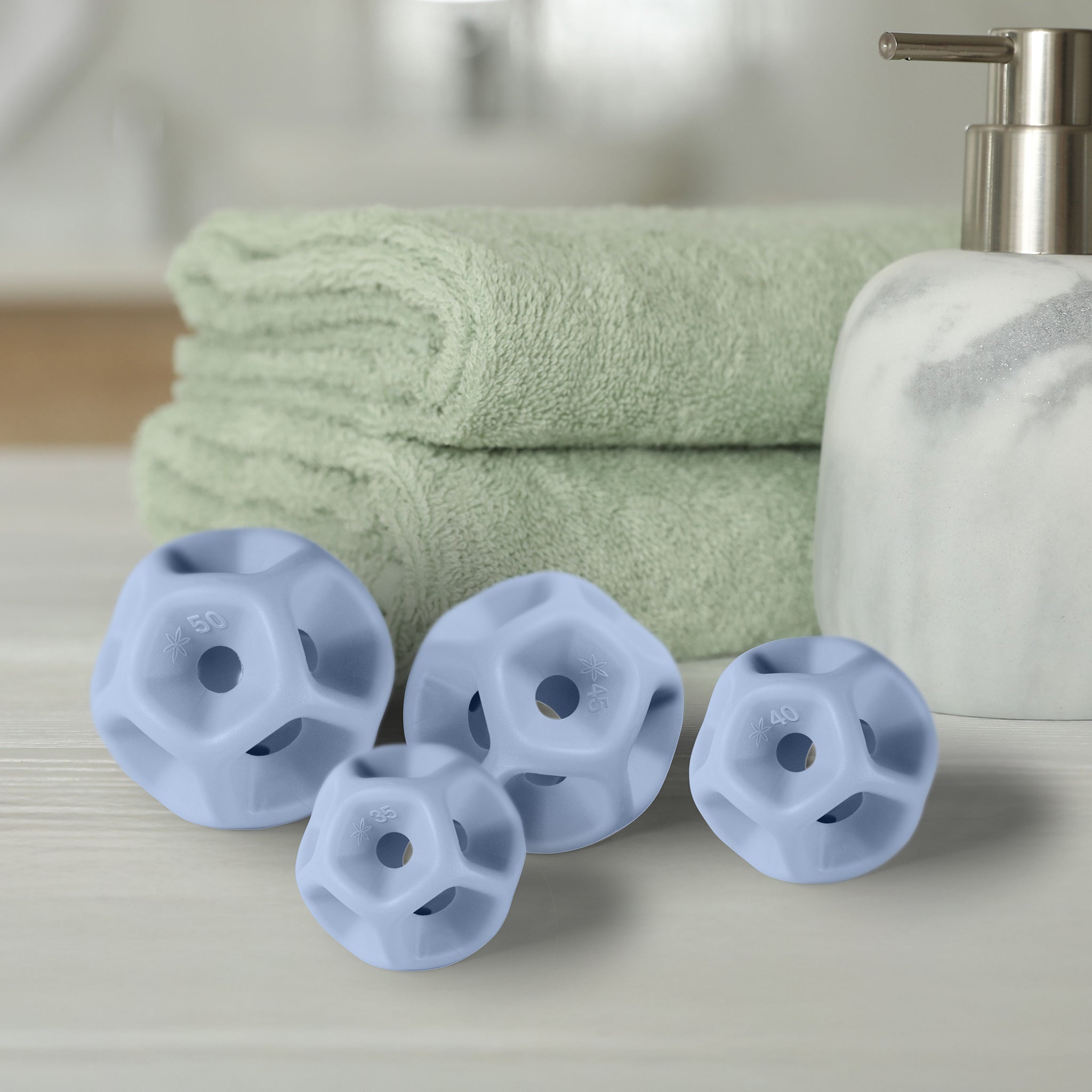 Green towels, a white soap dispenser, and purple silicone Soma Flex®  sizing seton a light surface.