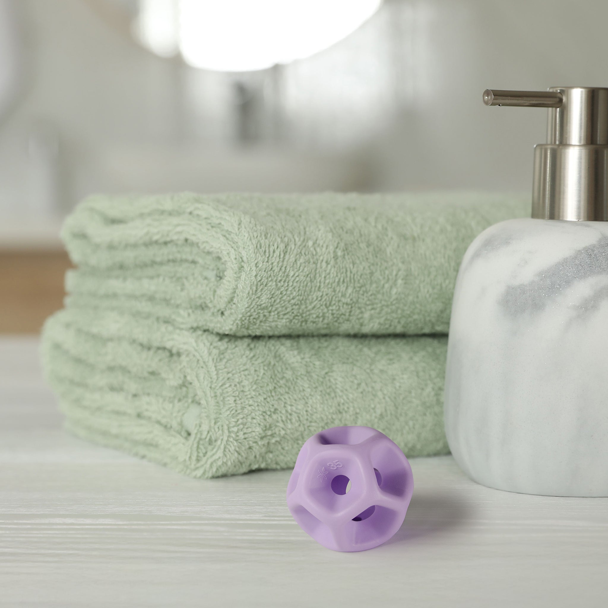 Green towels, a white soap dispenser, and purple silicone Soma Flex® 35  on a light surface.