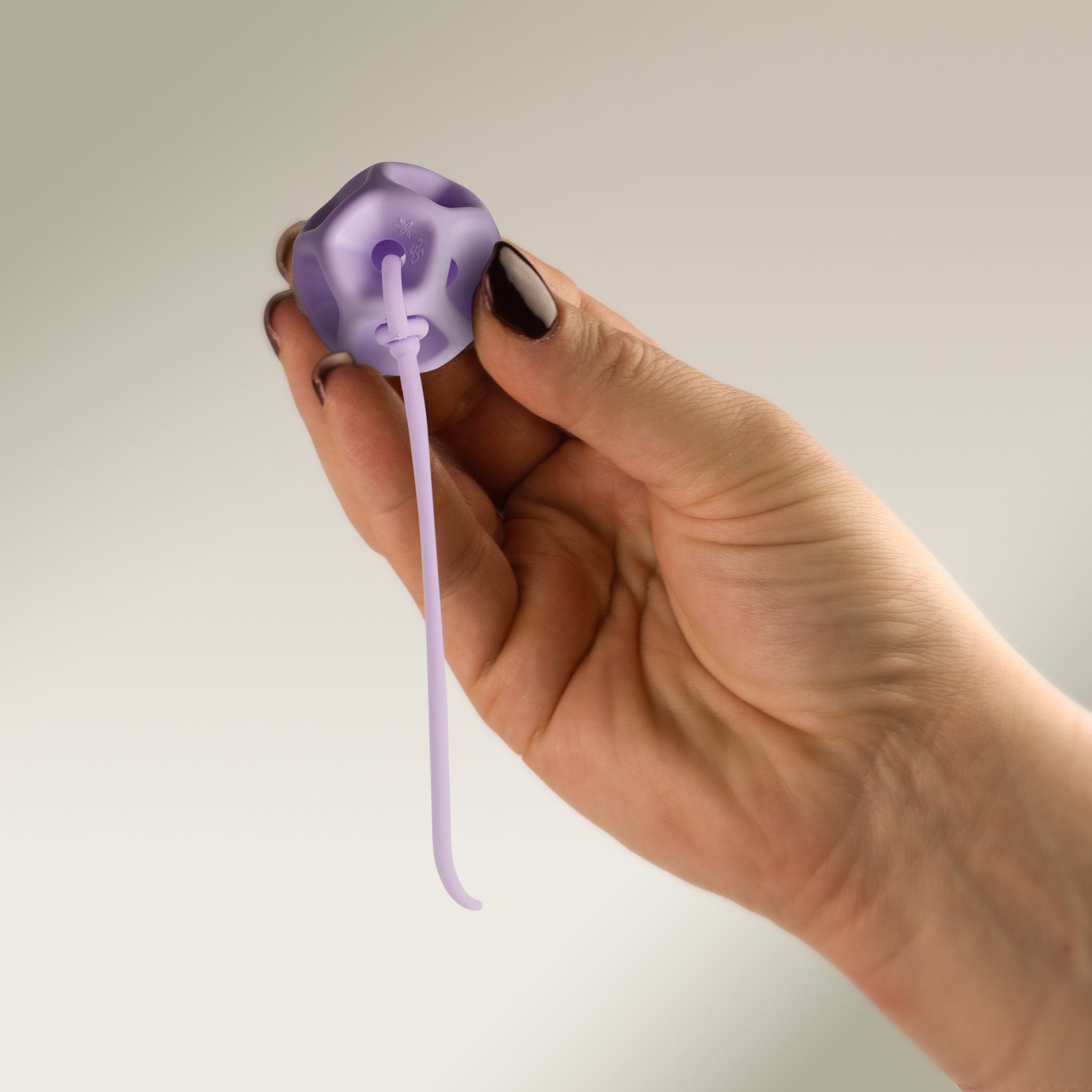 Hand holding a Soma Flex® 35 with removal cord attached on a plain background