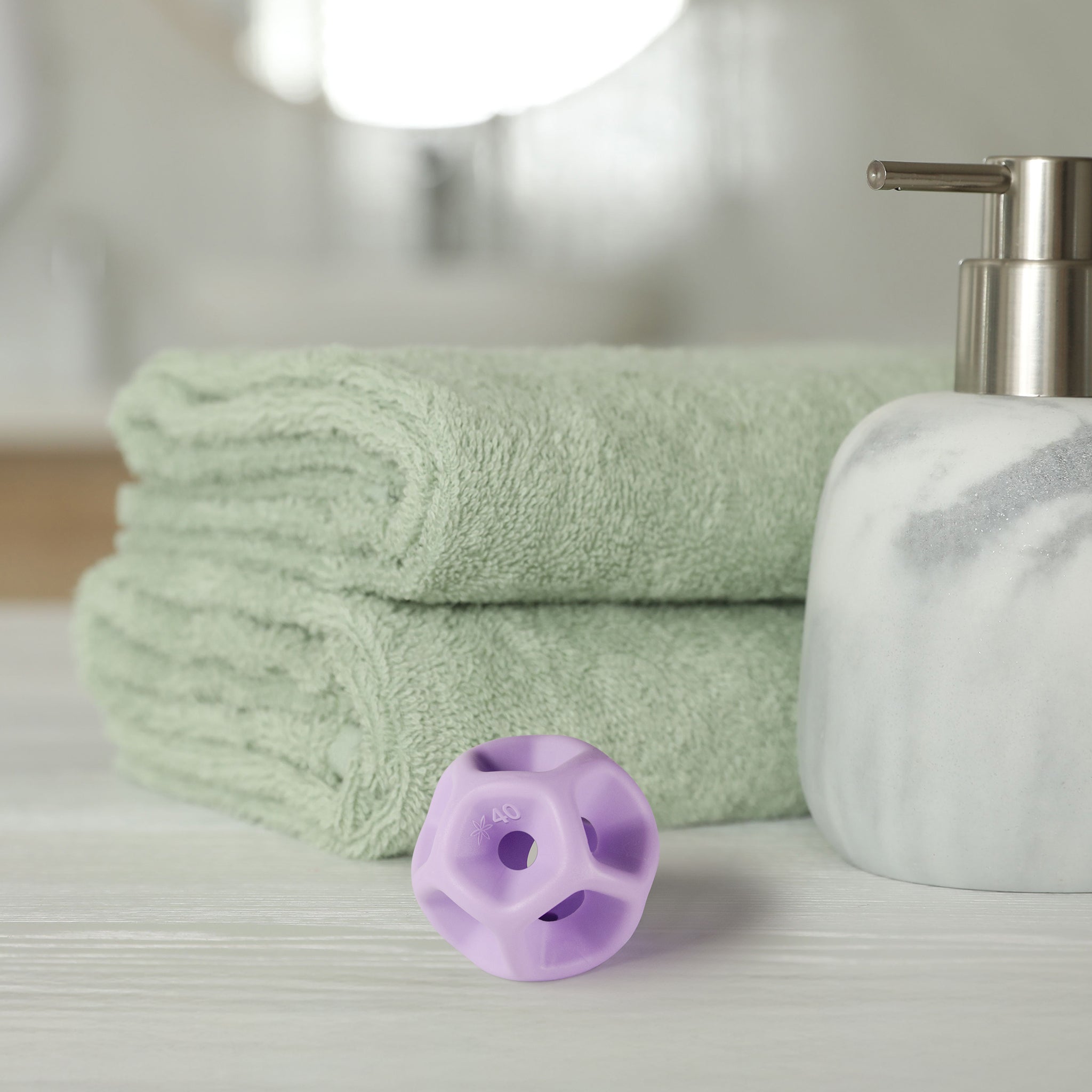 Green towels, a white soap dispenser, and purple silicone Soma Flex® 40 on a light surface.
