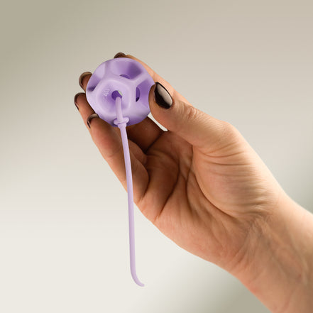 Hand holding a Soma Flex® 40 with removal cord attached on a plain background