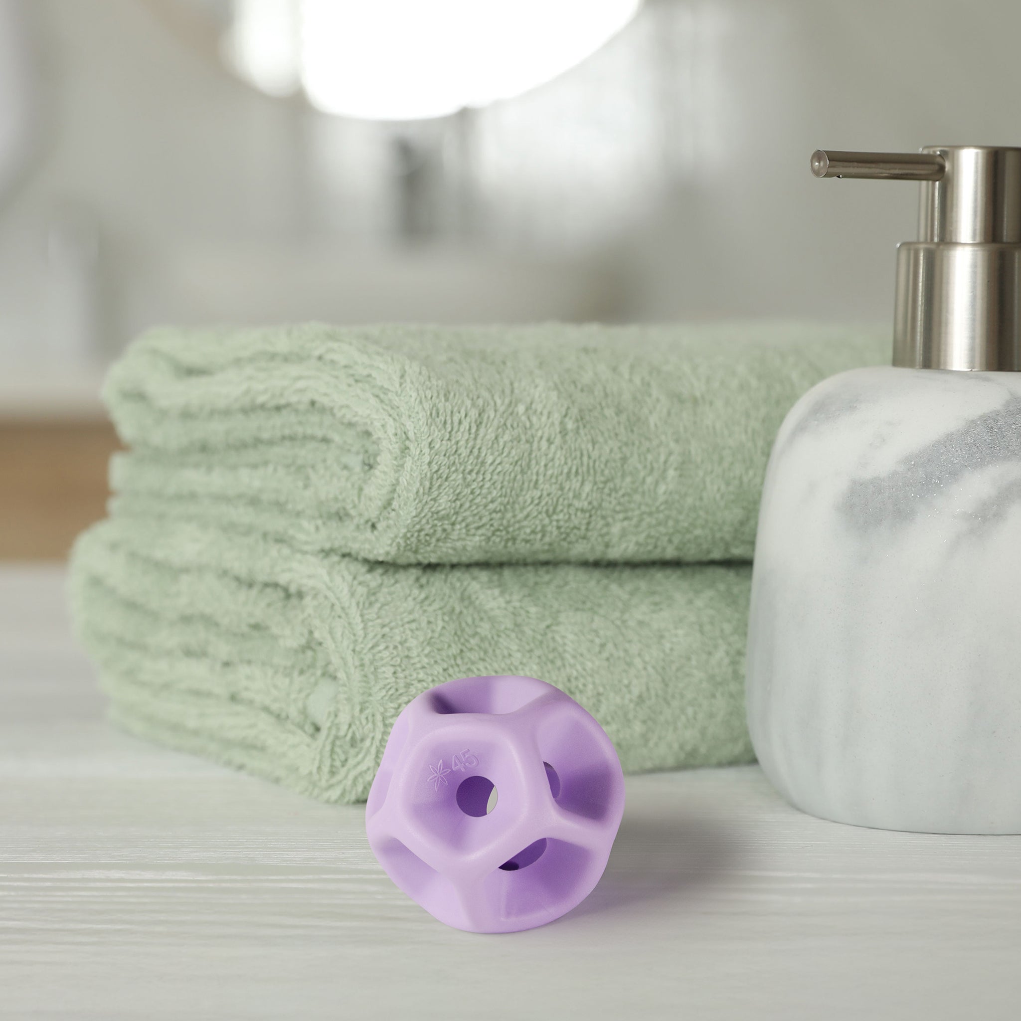 Green towels, a white soap dispenser, and purple silicone Soma Flex® 45  on a light surface.