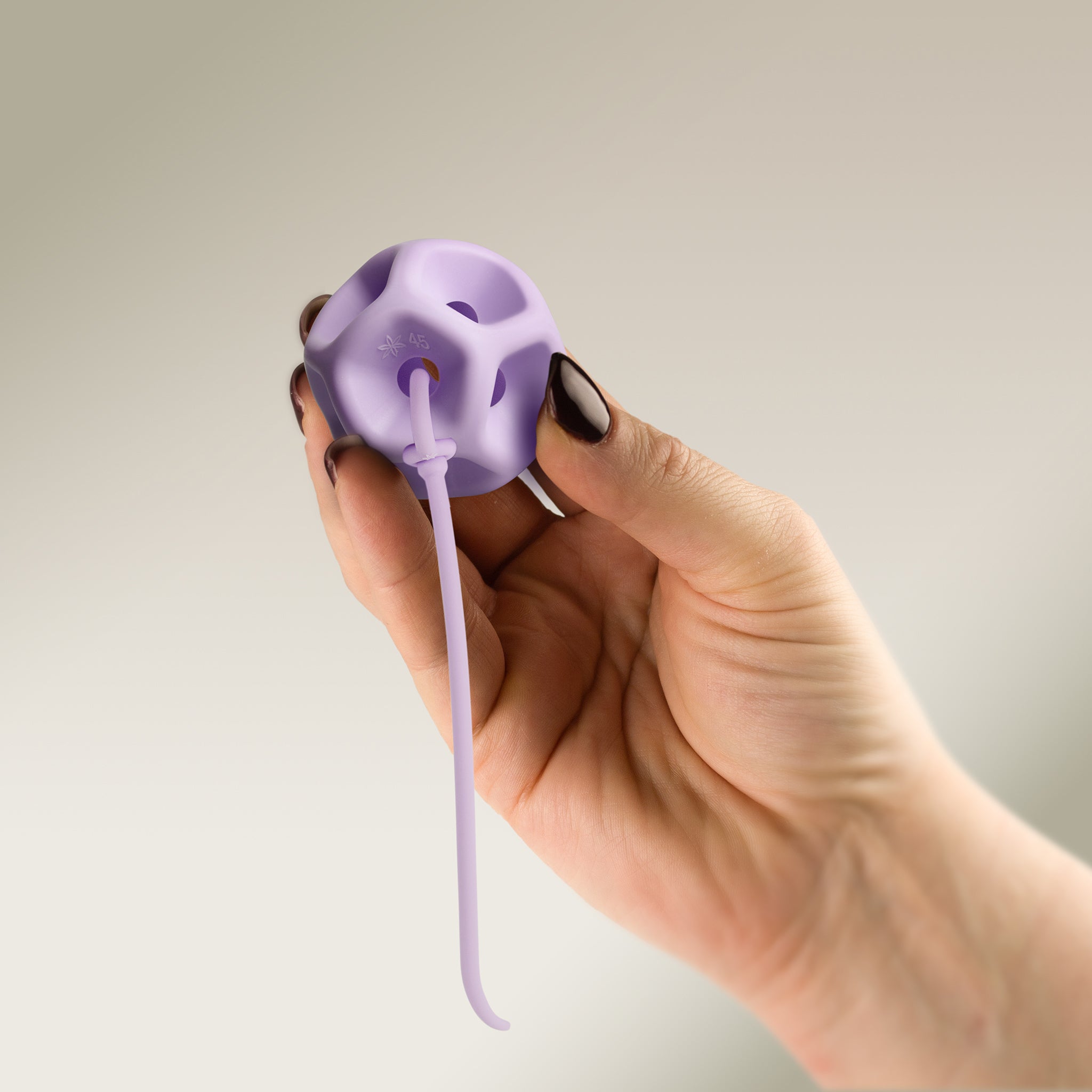 Hand holding a Soma Flex® 45 with removal cord attached on a plain background