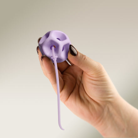 Hand holding a Soma Flex® 45 with removal cord attached on a plain background