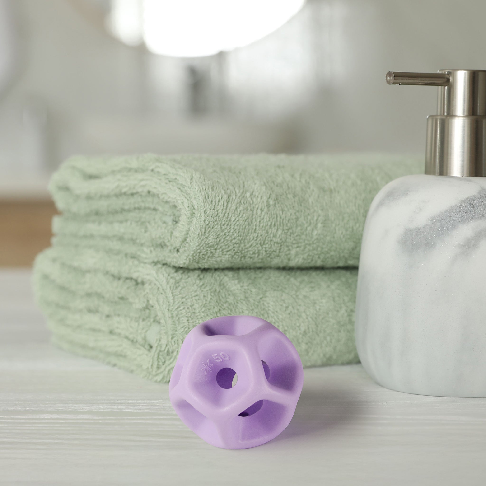 Green towels, a white soap dispenser, and purple silicone Soma Flex® 50 on a light surface.