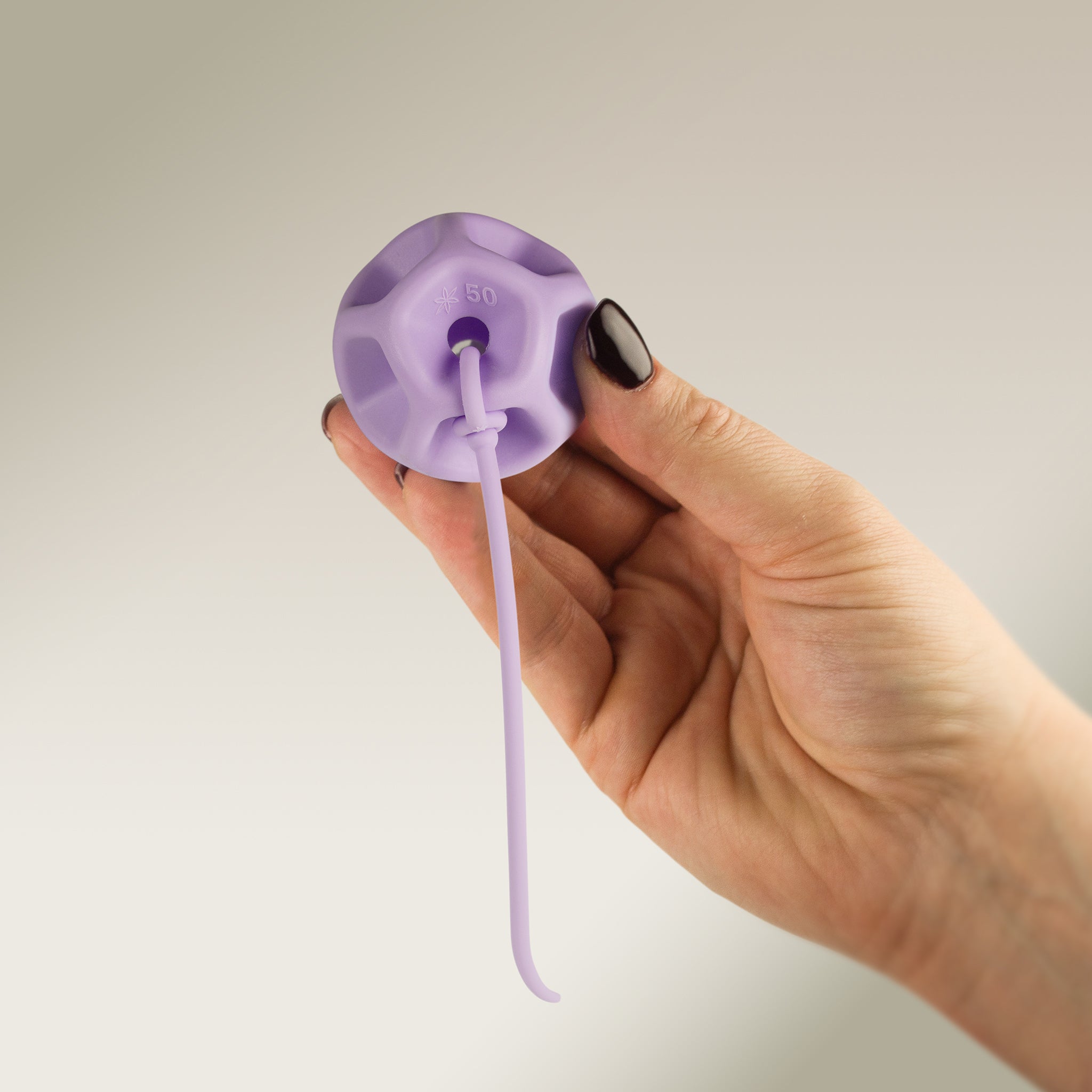 Hand holding a Soma Flex® 50 with removal cord against a plain background