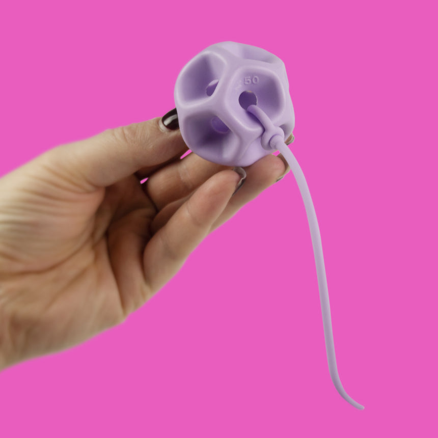 Hand holding a Soma Flex® 45 and removal cord against a pink background