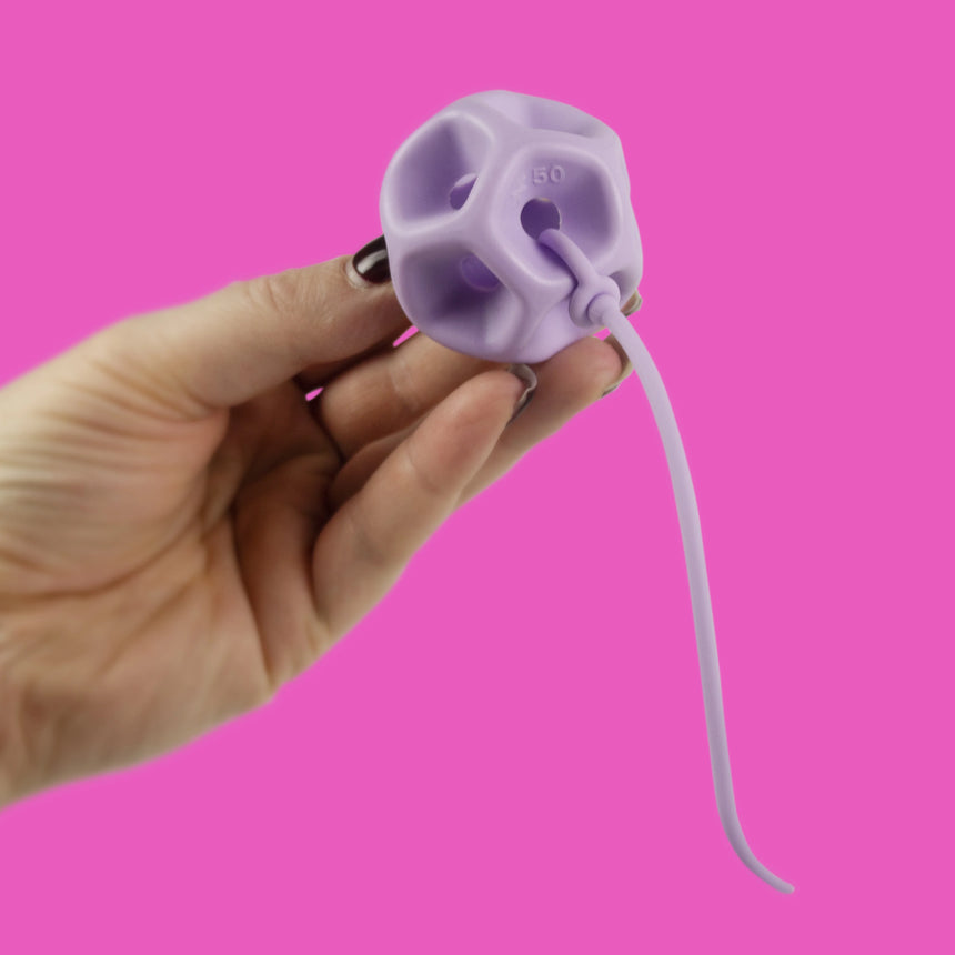 Hand holding a Soma Flex® 45 and removal cord against a pink background