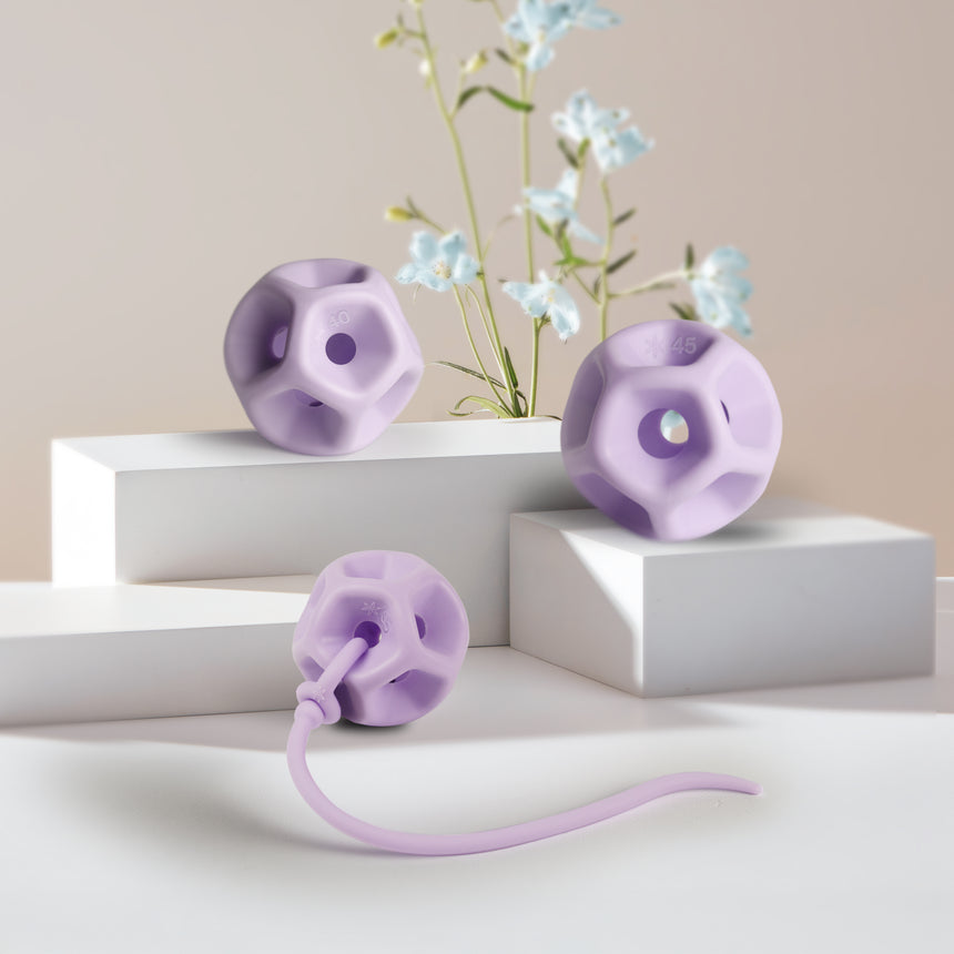 3 Purple silicone Soma Flex with a removal cord on a white surface with decorative flowers.