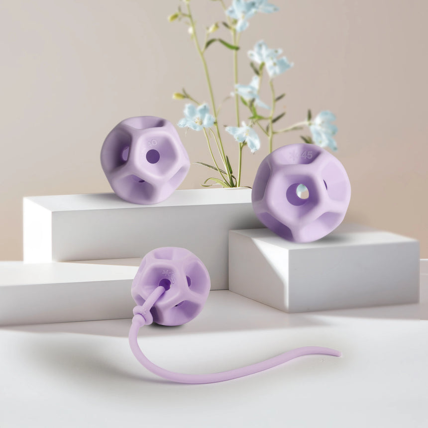 3 Purple silicone Soma Flex with a removal cord on a white surface with decorative flowers.