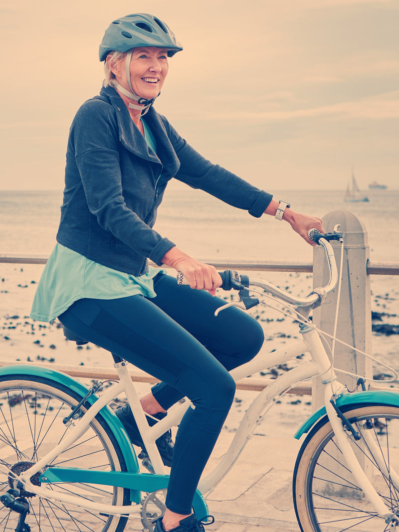 Woman riding a bicycle on a beach with a scenic background