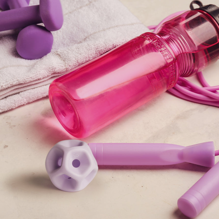Pink water bottle, purple dumbbells, and jump rope on a towel with Soma Flex 40 at the front